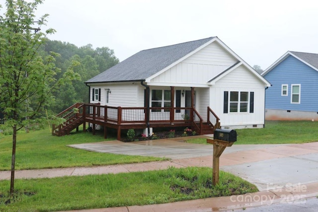 view of front facade featuring a porch, a shingled roof, stairs, and a front yard