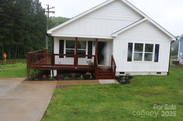 view of front of house with board and batten siding, a front lawn, central AC, covered porch, and crawl space