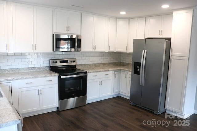 kitchen with white cabinets, dark wood-style floors, tasteful backsplash, and appliances with stainless steel finishes