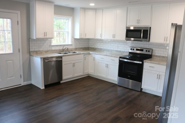 kitchen featuring a sink, decorative backsplash, dark wood-type flooring, appliances with stainless steel finishes, and white cabinetry