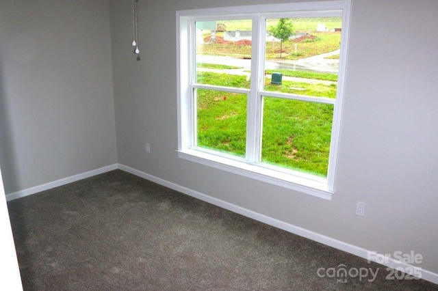 empty room with baseboards and dark carpet