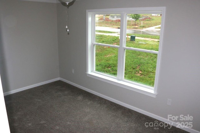 unfurnished room featuring baseboards and dark carpet