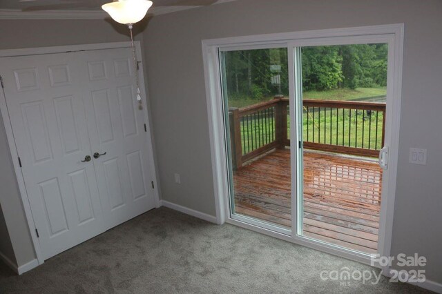 doorway featuring baseboards, carpet, and crown molding