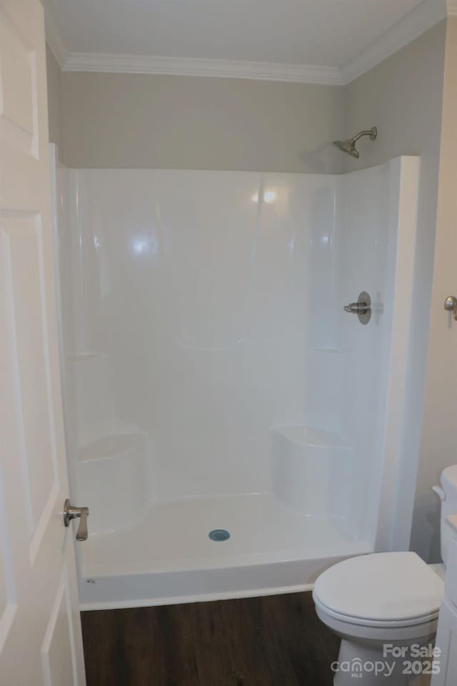 full bathroom with wood finished floors, toilet, a shower, and ornamental molding