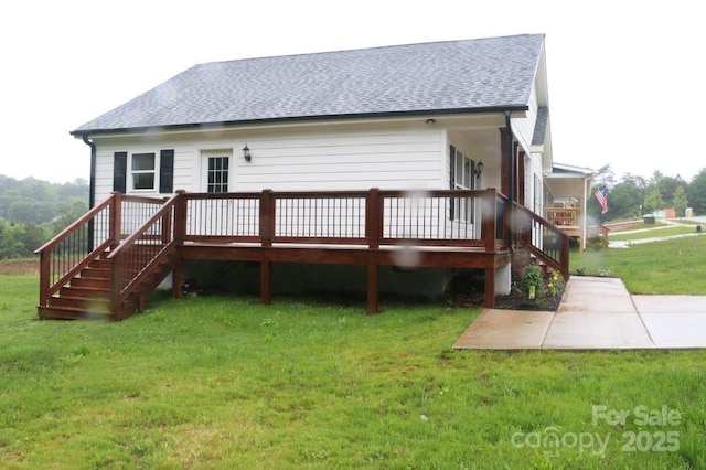 back of property featuring a yard, stairway, and roof with shingles