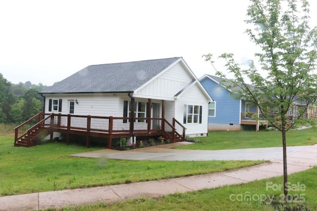 view of front of home with a front lawn, stairway, roof with shingles, a deck, and crawl space