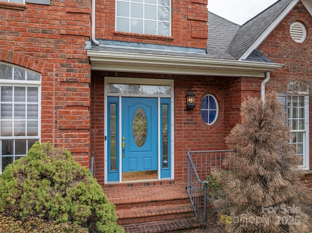 property entrance with brick siding and a shingled roof