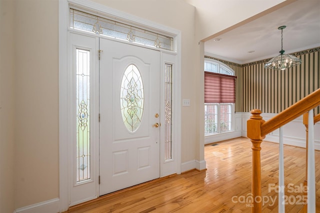 entryway featuring stairway, visible vents, ornamental molding, light wood-style floors, and a chandelier