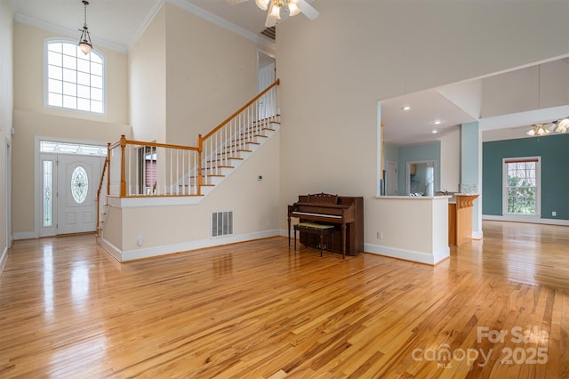 unfurnished living room featuring visible vents, baseboards, ceiling fan, stairway, and hardwood / wood-style flooring