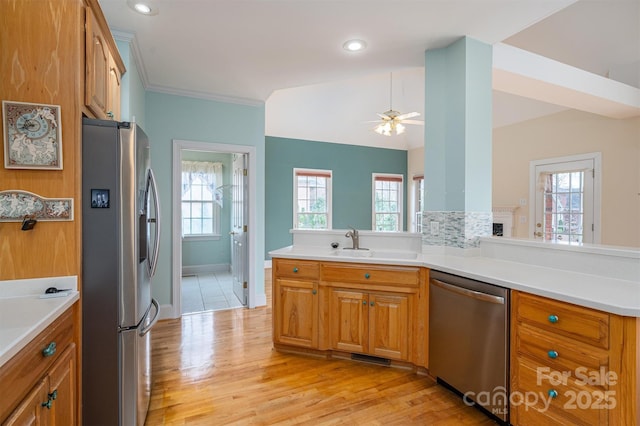 kitchen featuring a peninsula, a wealth of natural light, brown cabinets, and appliances with stainless steel finishes