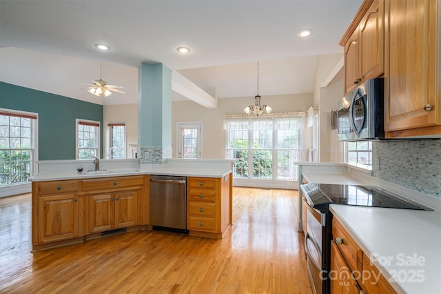 kitchen with light wood-type flooring, a sink, tasteful backsplash, appliances with stainless steel finishes, and light countertops