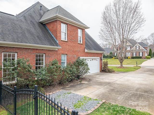 view of side of home featuring concrete driveway, a lawn, brick siding, and roof with shingles