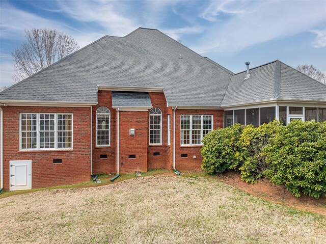 back of property featuring a lawn, roof with shingles, a sunroom, crawl space, and brick siding