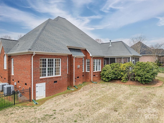 back of house with brick siding, roof with shingles, a lawn, and fence