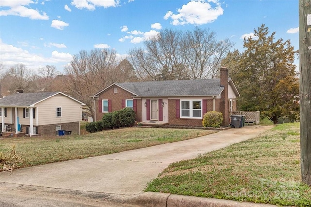 ranch-style house featuring brick siding, concrete driveway, a chimney, and a front lawn