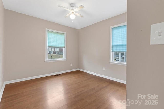 empty room with baseboards, visible vents, a wealth of natural light, and ceiling fan