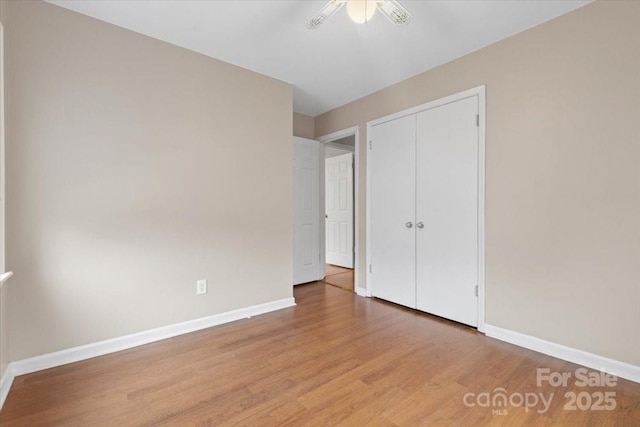 unfurnished bedroom with a closet, baseboards, light wood-style flooring, and a ceiling fan