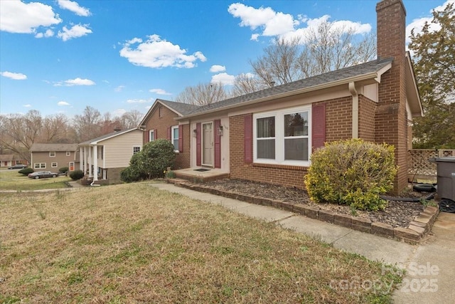 view of front of property featuring a front yard, brick siding, and a chimney