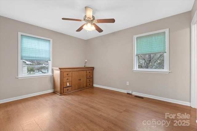 spare room with visible vents, ceiling fan, baseboards, and wood finished floors