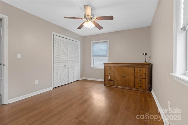 unfurnished bedroom featuring a closet, baseboards, and wood finished floors