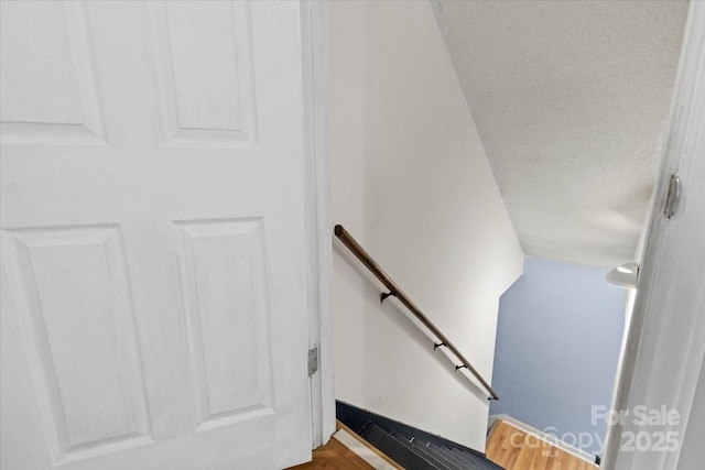 stairway with wood finished floors and a textured ceiling