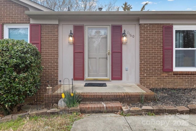 view of exterior entry featuring brick siding