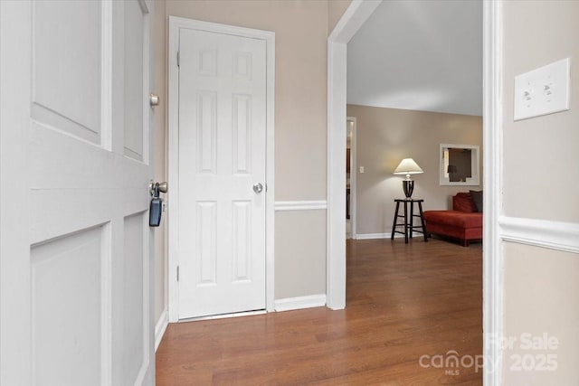 corridor featuring baseboards and wood finished floors