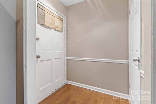 hallway featuring wood finished floors and baseboards