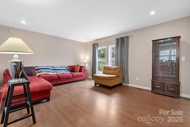 living room featuring visible vents, baseboards, and wood finished floors