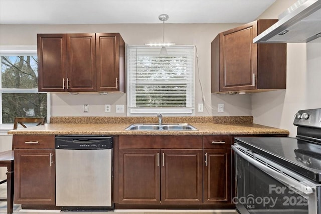 kitchen featuring a sink, stainless steel appliances, light countertops, pendant lighting, and wall chimney exhaust hood