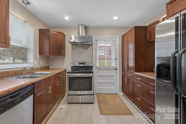 kitchen with wall chimney range hood, decorative light fixtures, recessed lighting, stainless steel appliances, and a sink