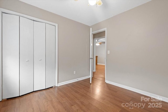 unfurnished bedroom with a closet, baseboards, and wood finished floors