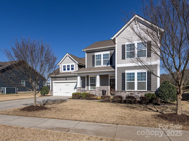craftsman-style home with a front yard, a porch, an attached garage, concrete driveway, and stone siding