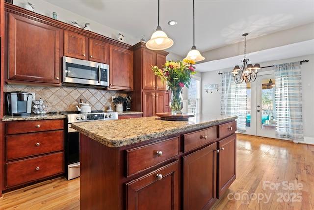 4858 Sagittarius Cir, Denver, NC 28037 - kitchen with stainless steel appliances, light wood-type flooring, backsplash, hanging light fixtures, and a kitchen island