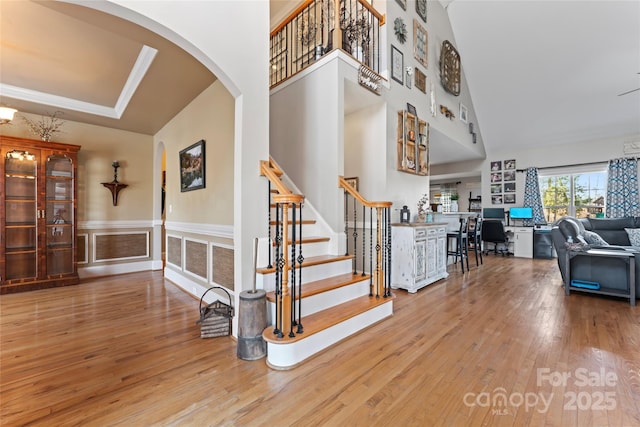 4858 Sagittarius Cir, Denver, NC 28037 - staircase featuring arched walkways, wood finished floors, a high ceiling, and a wainscoted wall