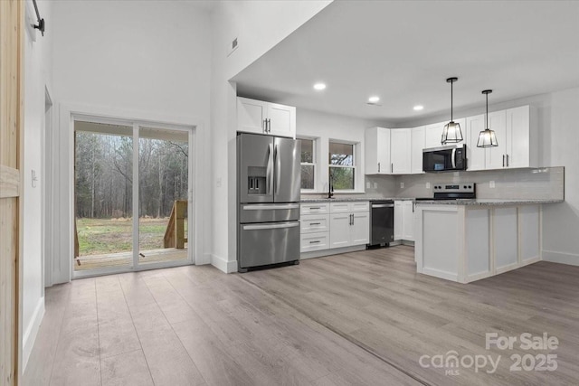 kitchen featuring decorative backsplash, white cabinets, light wood-type flooring, and stainless steel appliances