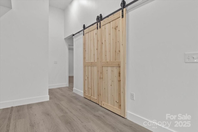 interior space featuring baseboards, a barn door, and wood finished floors