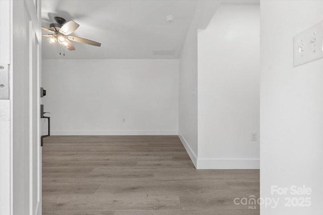 spare room with baseboards, wood finished floors, visible vents, and ceiling fan