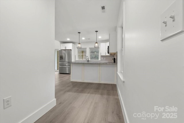 kitchen with visible vents, white cabinetry, appliances with stainless steel finishes, a peninsula, and light wood finished floors