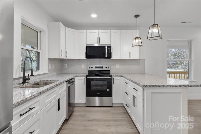 kitchen with light wood-type flooring, a sink, white cabinetry, appliances with stainless steel finishes, and a peninsula