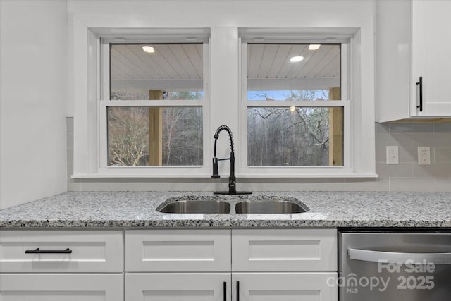 kitchen with white cabinetry, backsplash, a sink, dishwasher, and a wealth of natural light