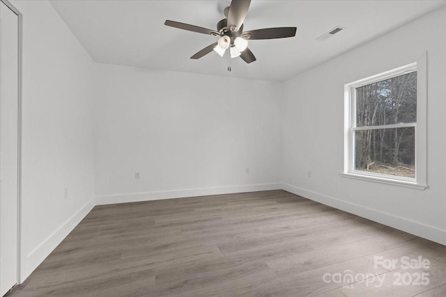 spare room with visible vents, wood finished floors, baseboards, and ceiling fan