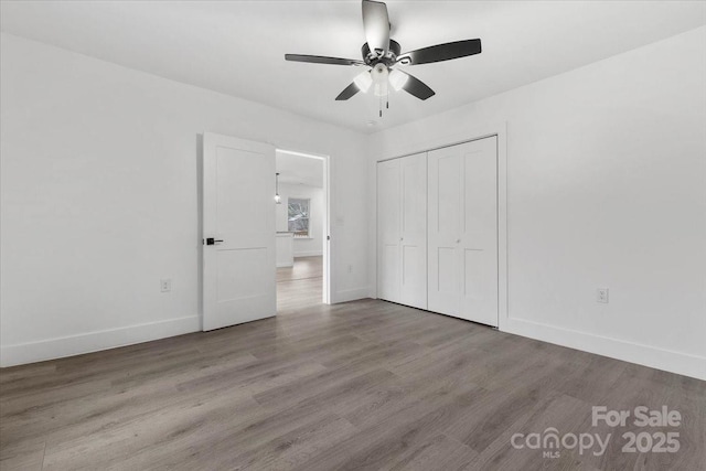 unfurnished bedroom with a closet, baseboards, and wood finished floors