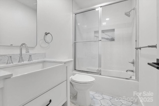 bathroom with vanity, toilet, and combined bath / shower with glass door