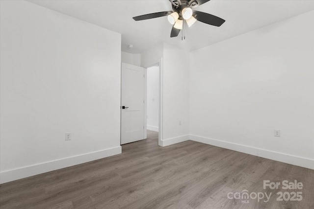 empty room featuring a ceiling fan, baseboards, and wood finished floors