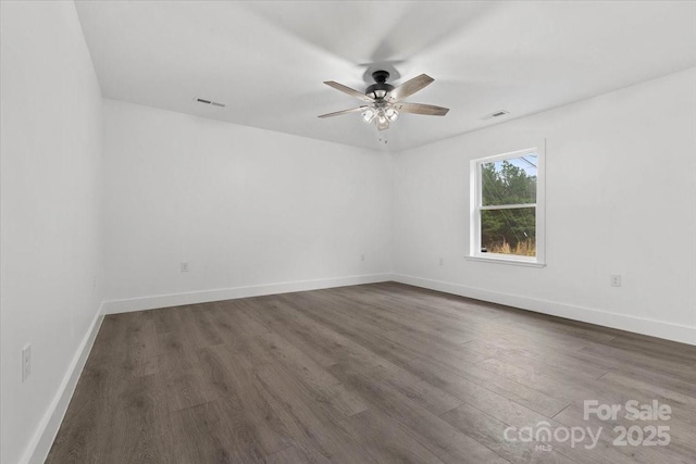 unfurnished room featuring a ceiling fan, dark wood-style floors, visible vents, and baseboards