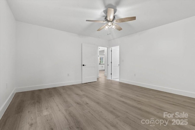 spare room featuring wood finished floors, baseboards, and ceiling fan