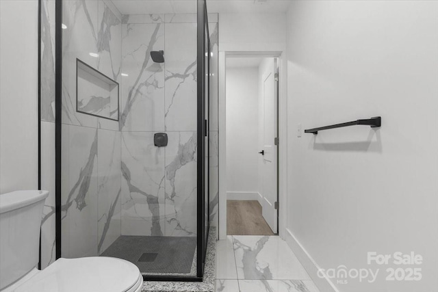 bathroom with a marble finish shower, toilet, and baseboards