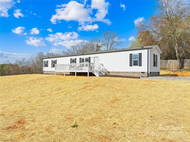 manufactured / mobile home featuring crawl space, a deck, a front lawn, and fence