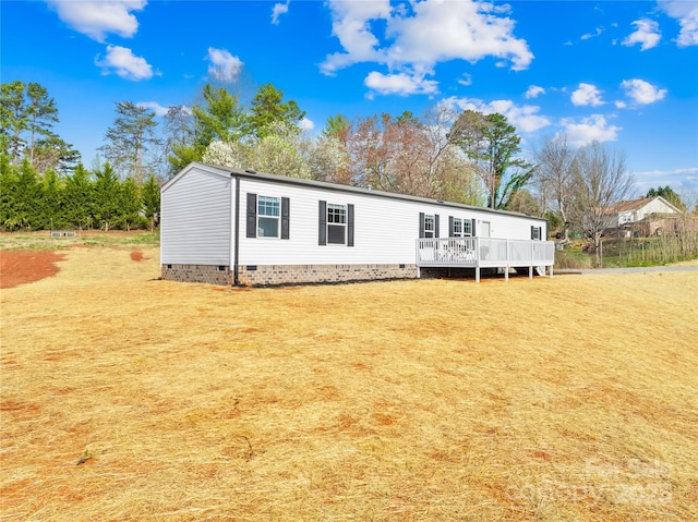 manufactured / mobile home featuring crawl space, a deck, and a front lawn